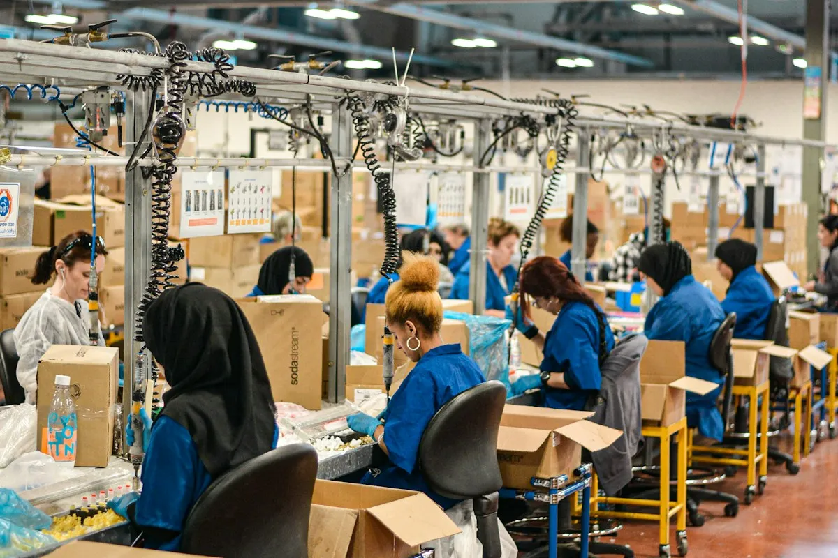 Workers in blue uniforms at an assembly line in a large factory