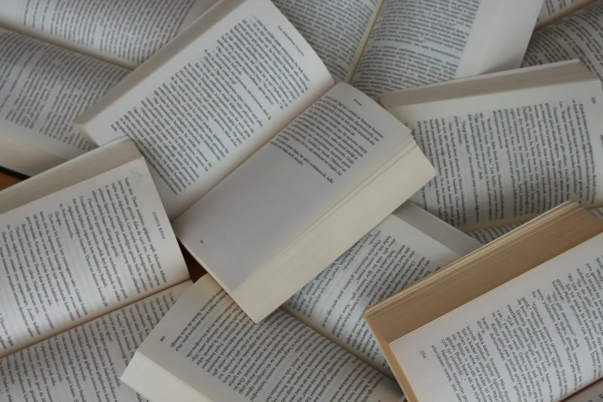 Open paperback books piled on top of one another