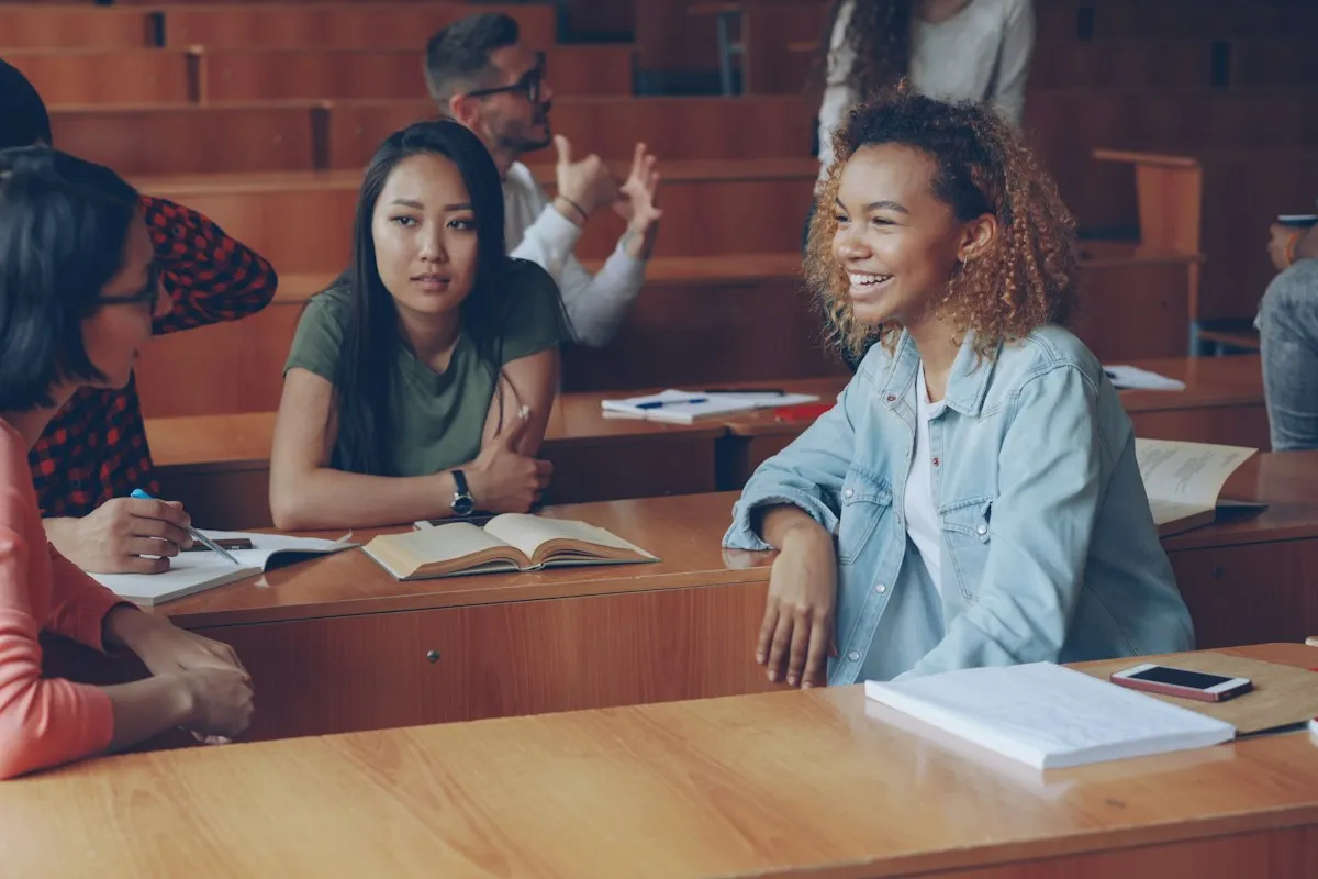 Students talking and laughing with each other across desks in a lecture hall